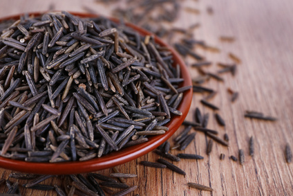 Black rice on plate on wooden background